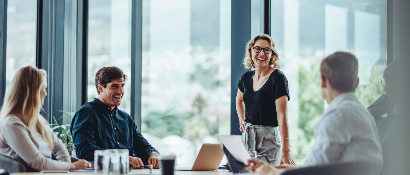 Office colleagues having casual discussion during meeting in conference room. Group of men and women sitting in conference room and smiling.