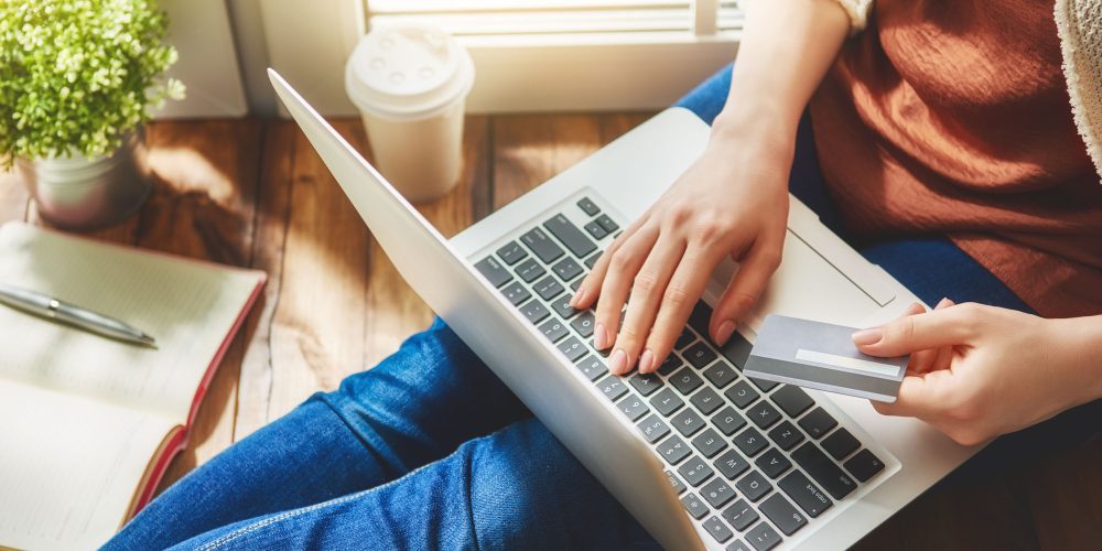Woman is holding credit card and using laptop computer. Online shopping concept. Close up.
